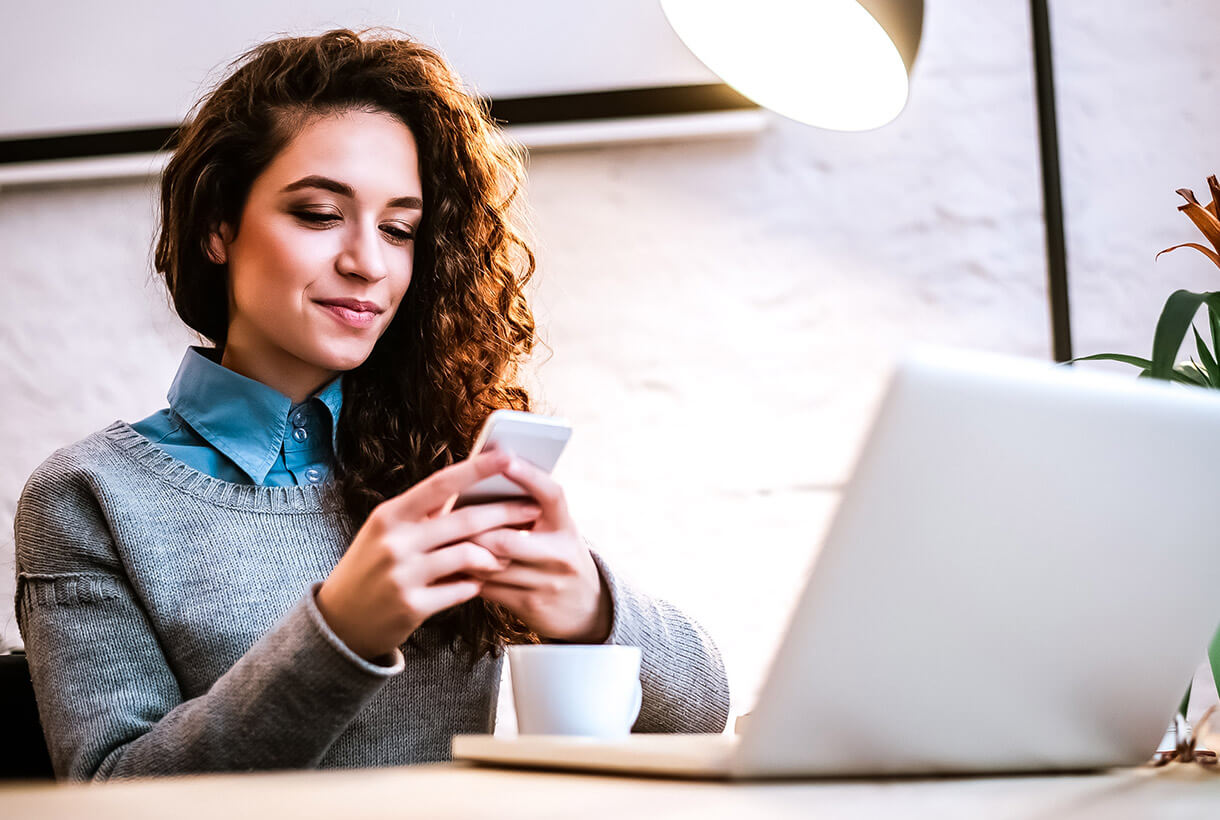 Woman smiling while looking at a smartphone