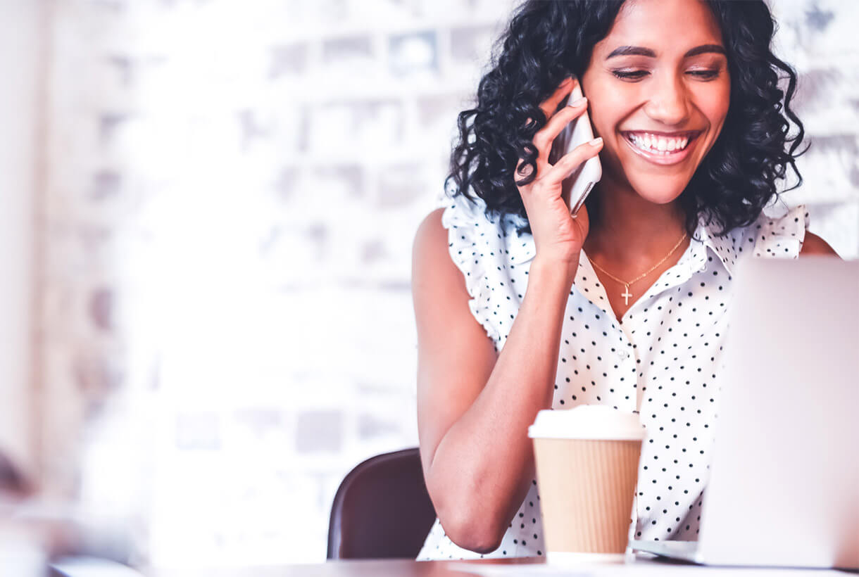 Photo of a woman at a cafe speaking on a smart phone