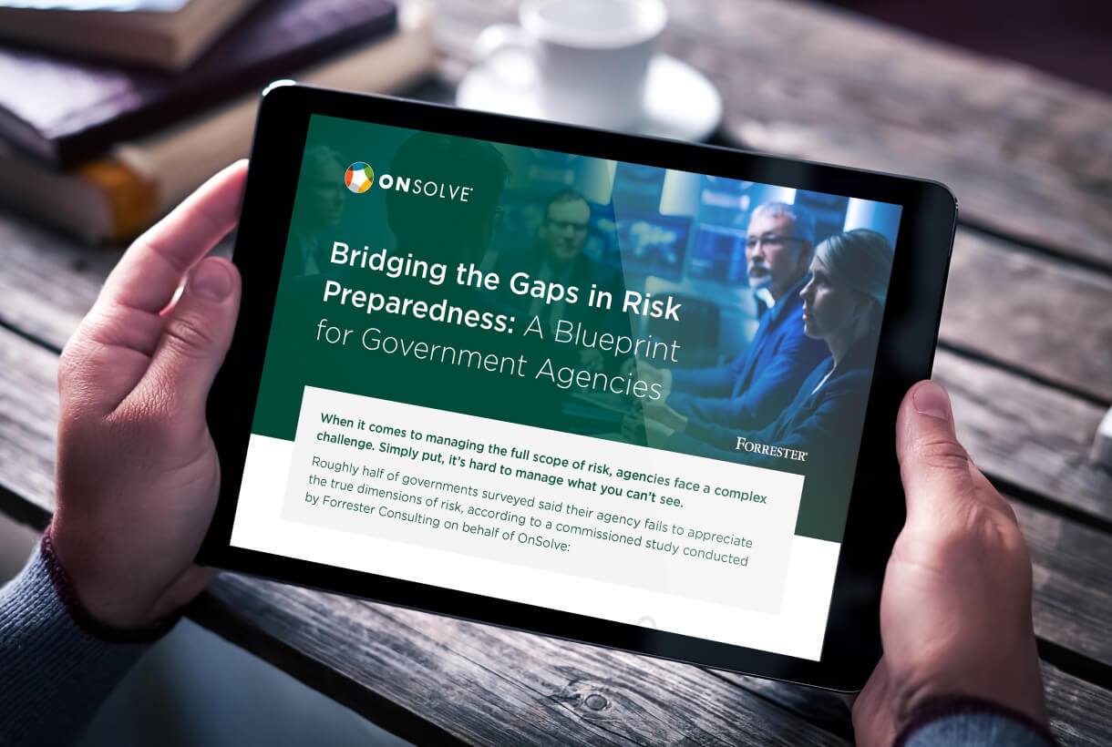 Photo of a person holding a tablet reading OnSolve's Forrester Government Spotlight Report